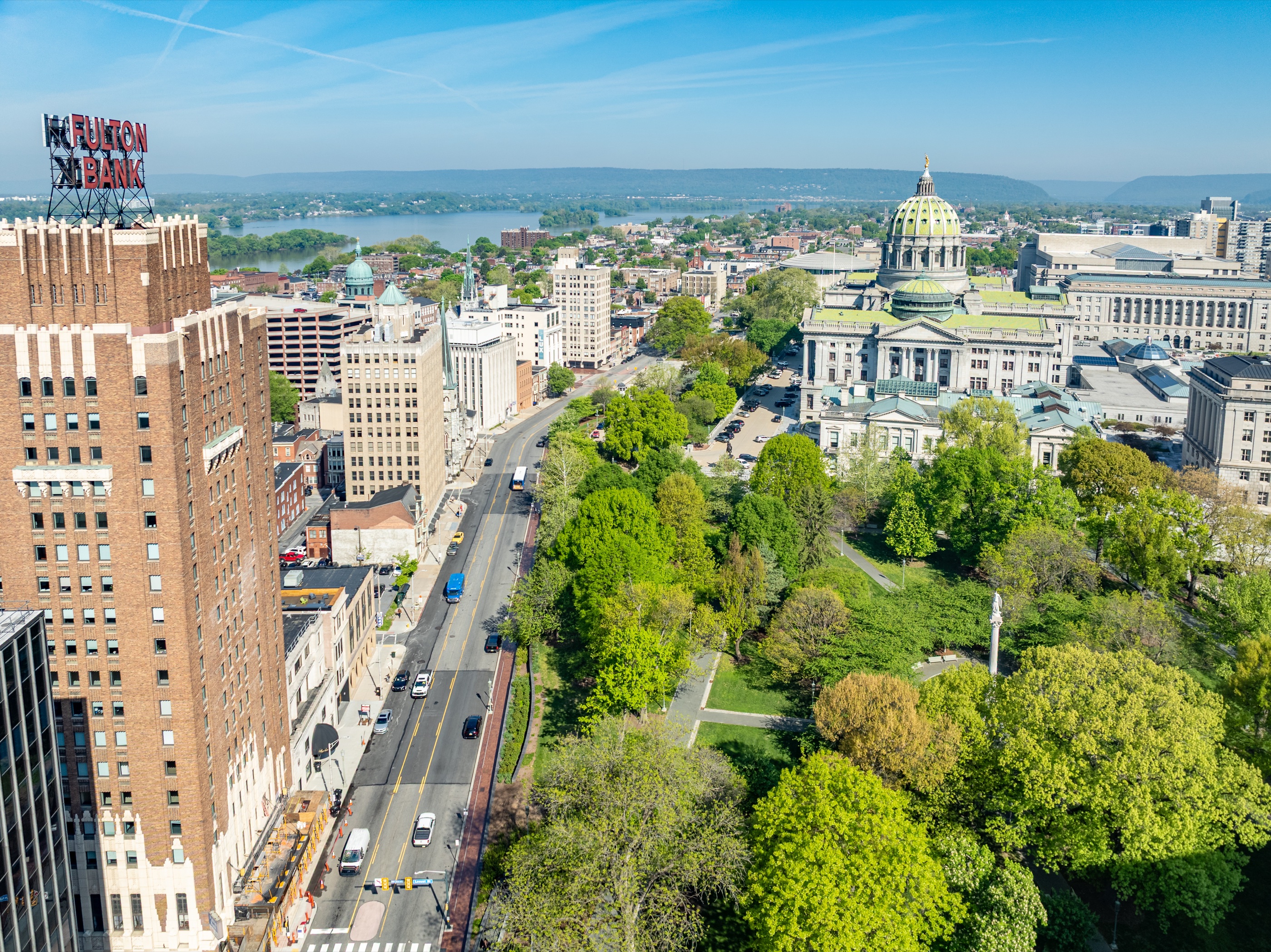 Spring aerial view across downtown Harrisburg toward the Pennsylvania State Capitol, Susquehanna River, and surrounding ridge line