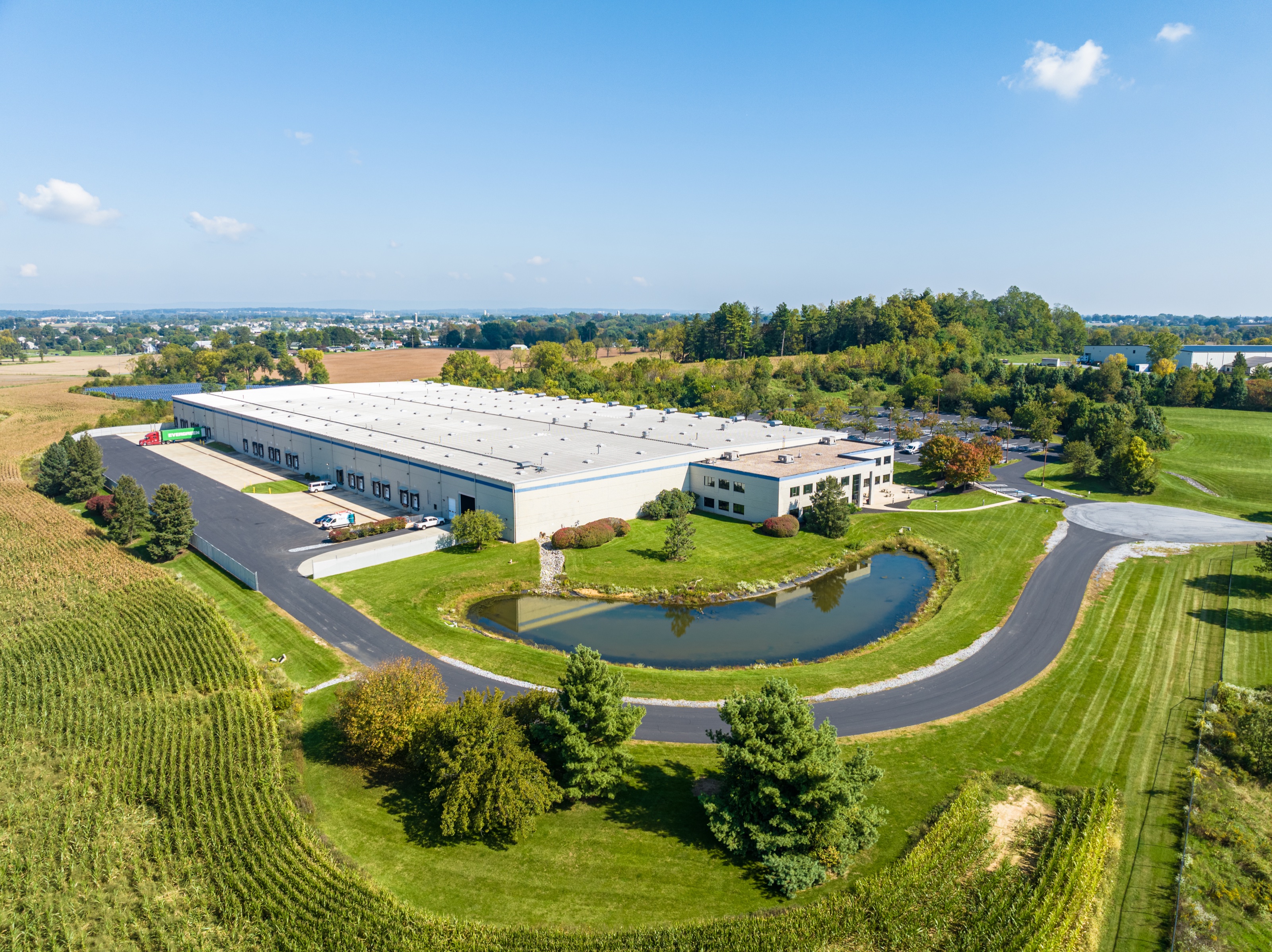Aerial view of a commercial property surrounded by water, fields, and regional roadways