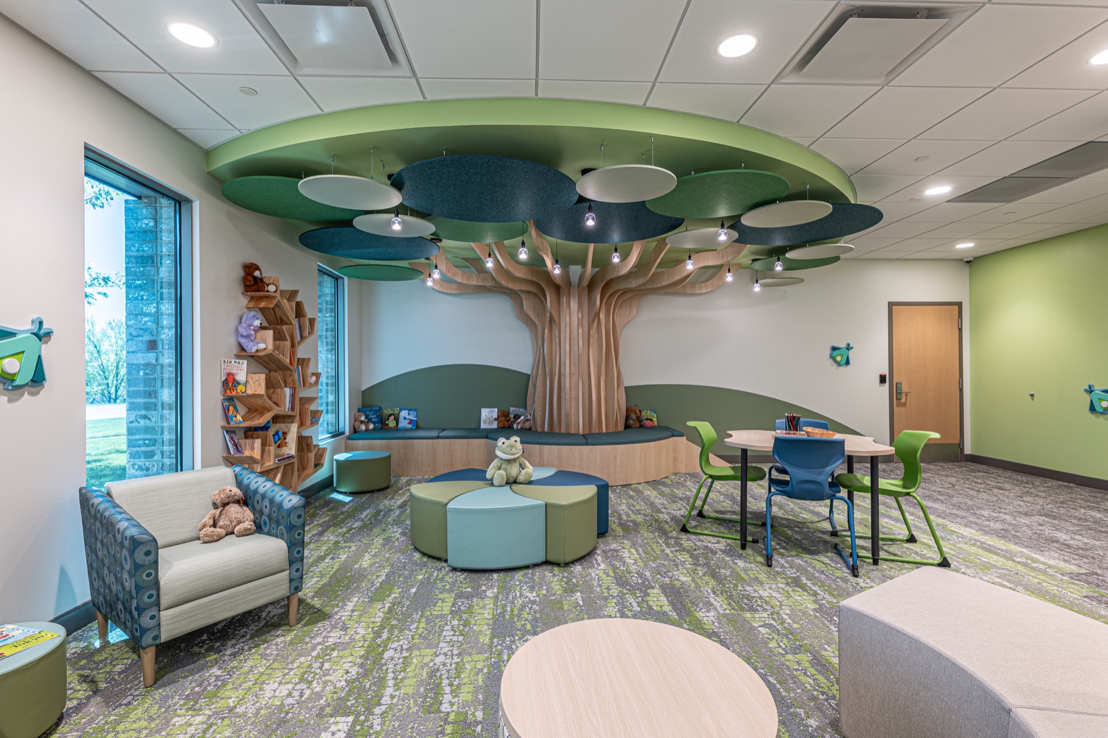 Colorful child-focused interior with a custom tree, reading area, and flexible seating